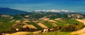 The snow-capped Sibillini Mountains rise above the rolling hills of Le Marche